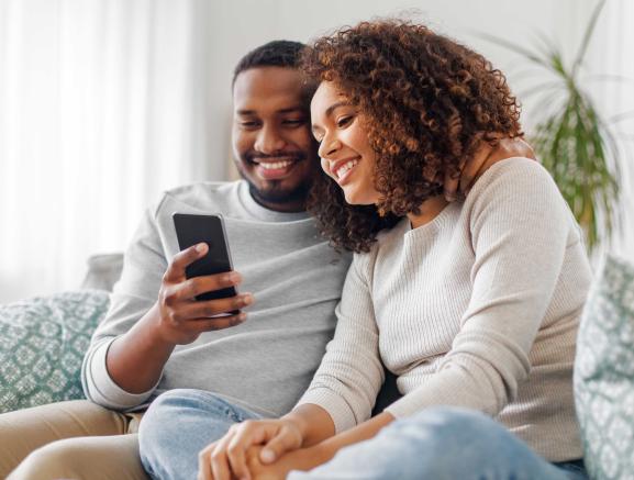two people sat on sofa looking at Prepay Power app on mobile phone